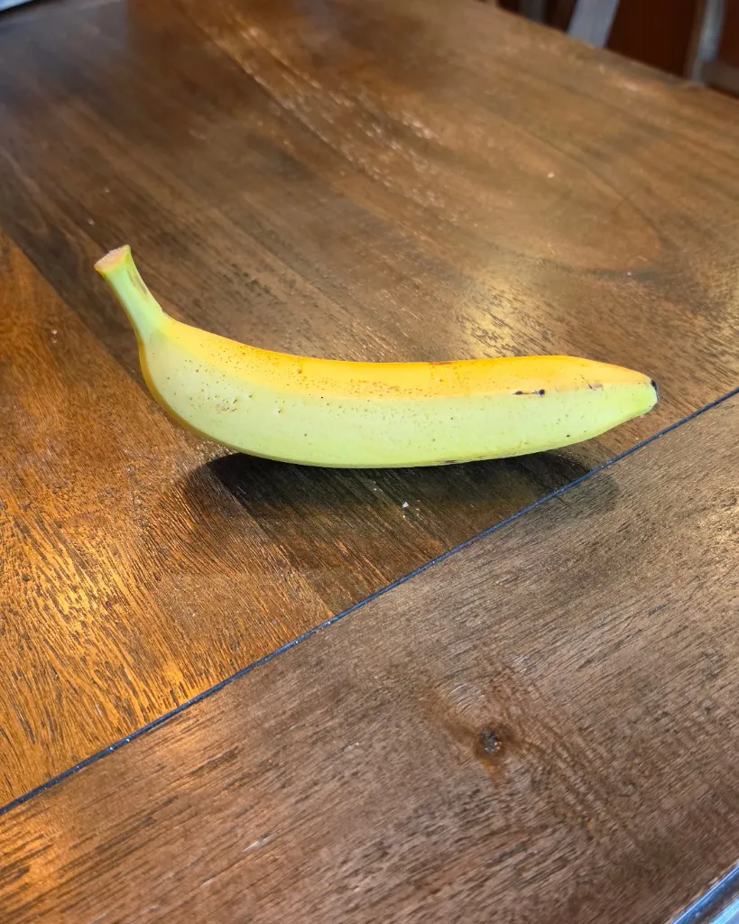 A banana sitting on a dining room table — raw unedited product photo